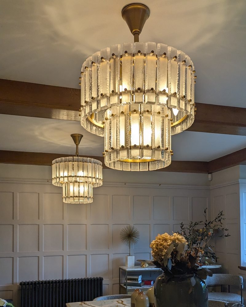 Pair of tiered glass chandeliers over a dining table in a panelled London dining room